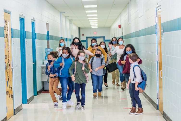 Des enfants courent dans un couloir d'école en portant des masques contre le Covid-19
