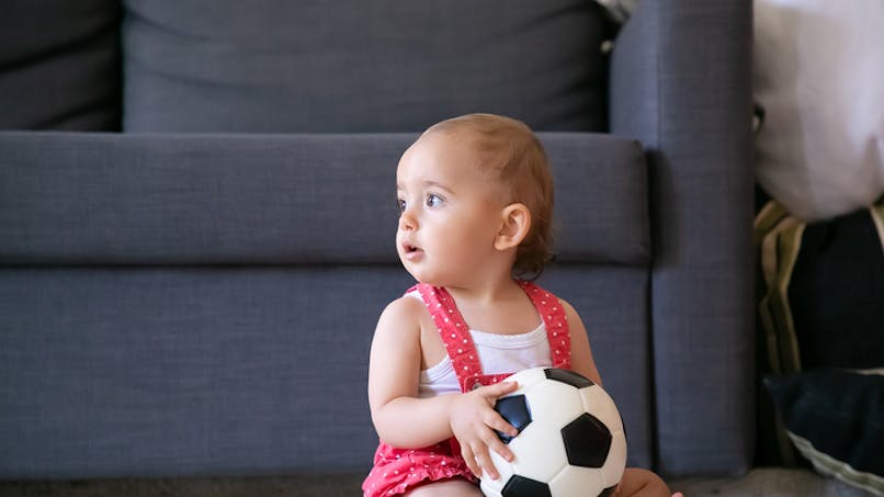 bébé avec ballon de foot dans le salon