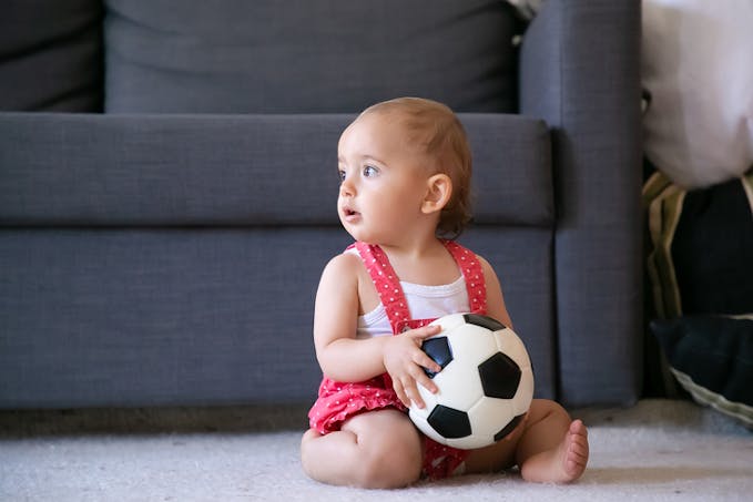 bébé avec ballon de foot dans le salon