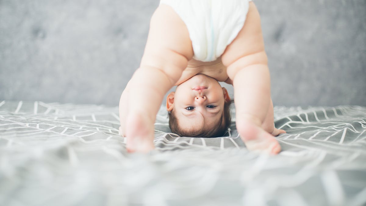 Un bébé portant une couche fait des acrobaties