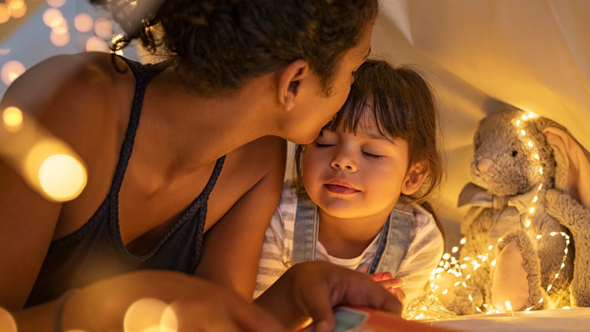 Une maman lit une histoire à sa petite fille avant de dormir