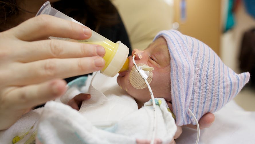 Un nouveau-né prématuré est nourri avec un biberon de lait maternel