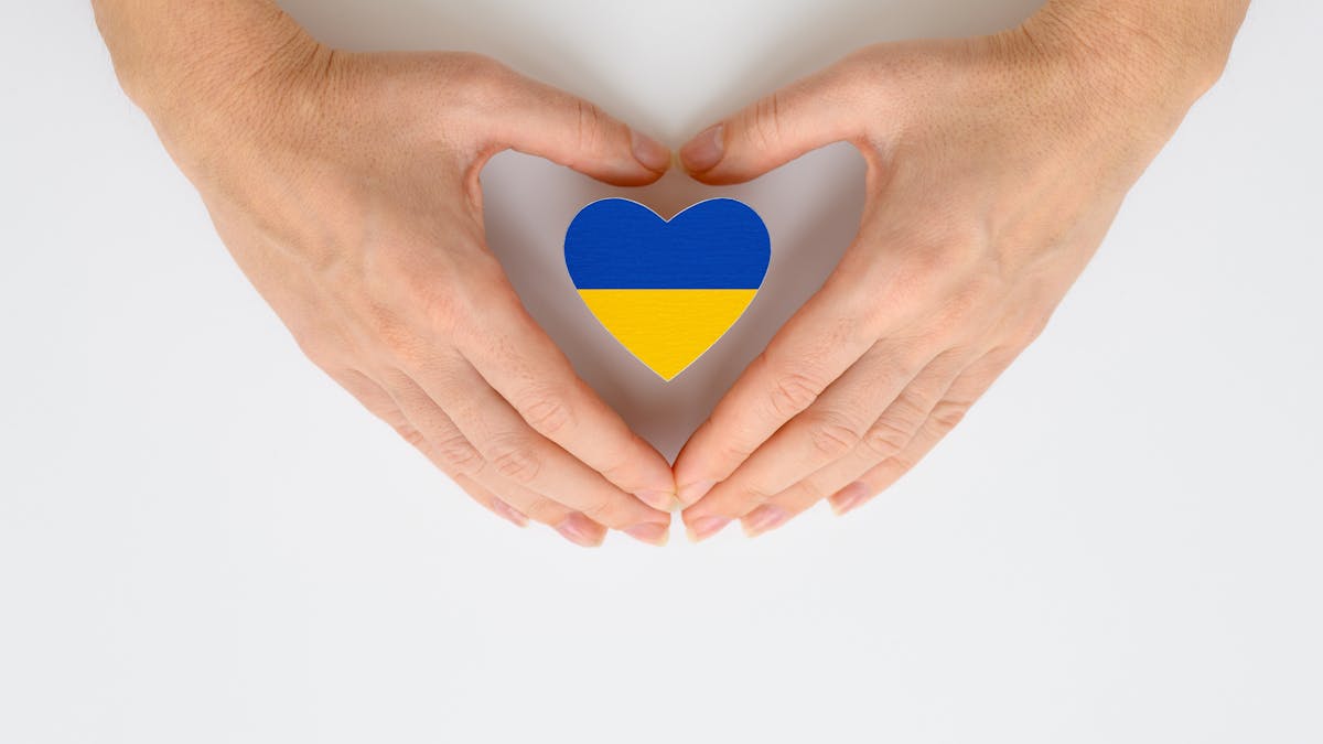 Deux mains encerclent un drapeau ukrainien en forme de coeur