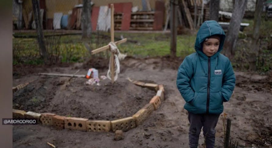 enfant ukrainien devant la tombe de sa mère