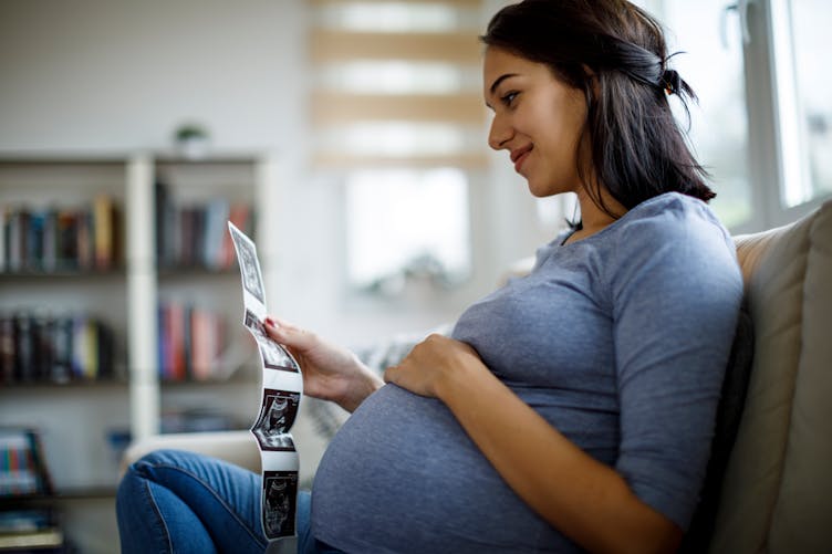 Une femme enceinte, sur le point d'accoucher, regarde des échographies.