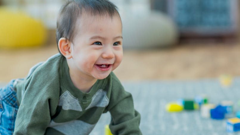bébé d'origine asiatique sur un tapis pour jouer