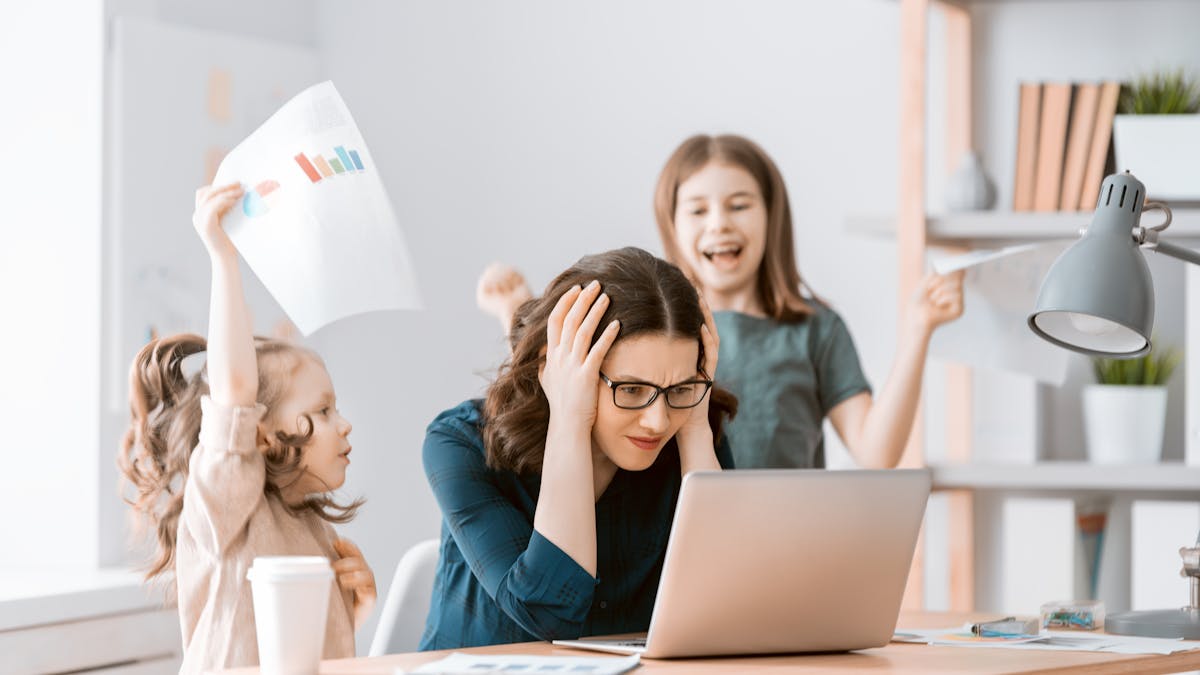 Une maman, derrière un écran d'ordinateur, peine à se concentrer avec ses enfants.