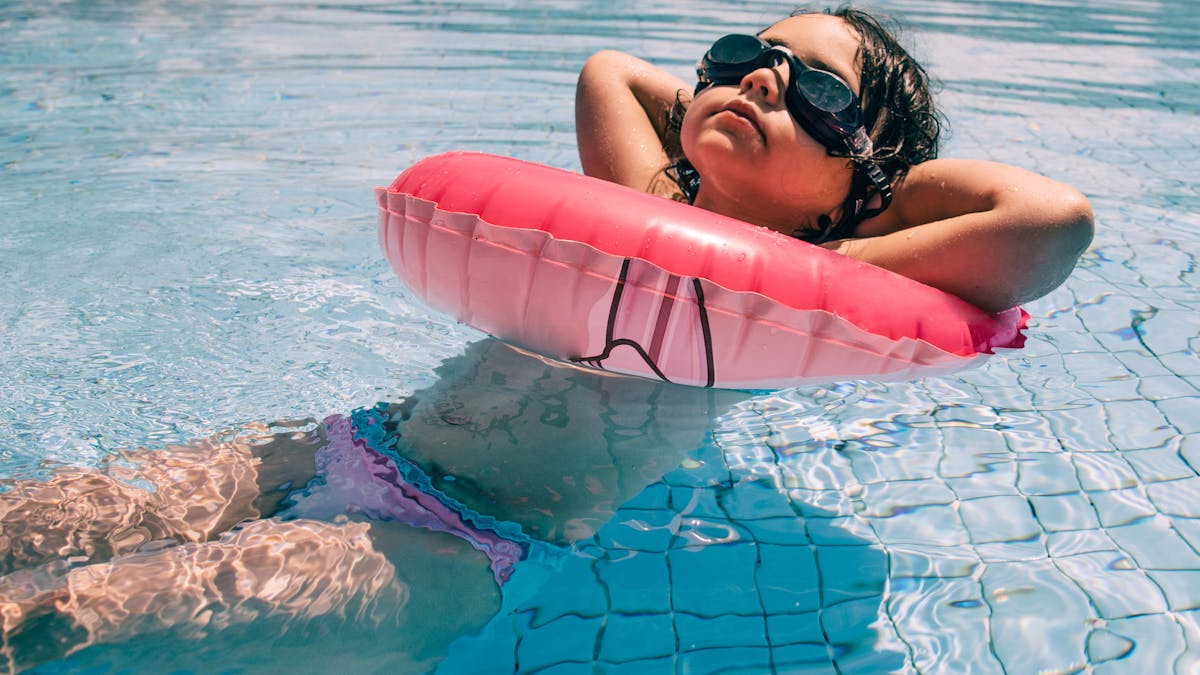 Une petite fille bronze dans une bouée de piscine.