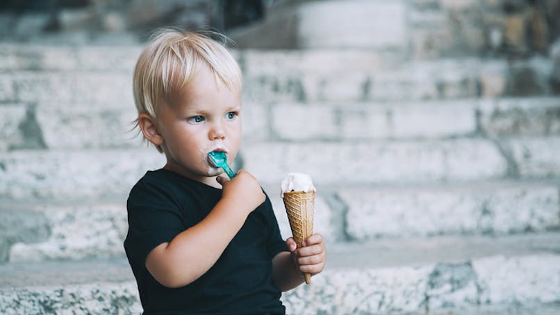 garçon mangeant une glace, assis sur des marches
