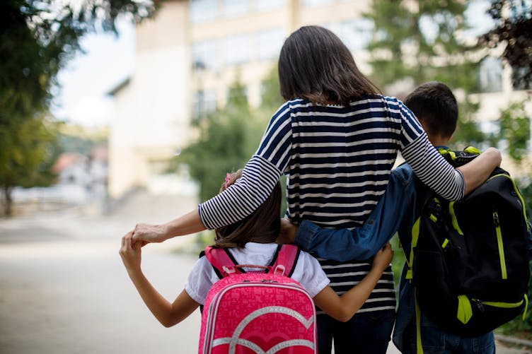 Une mère emmène ses enfants à l'école.
