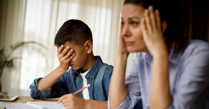 Un enfant et son parent peinent à faire des devoirs.