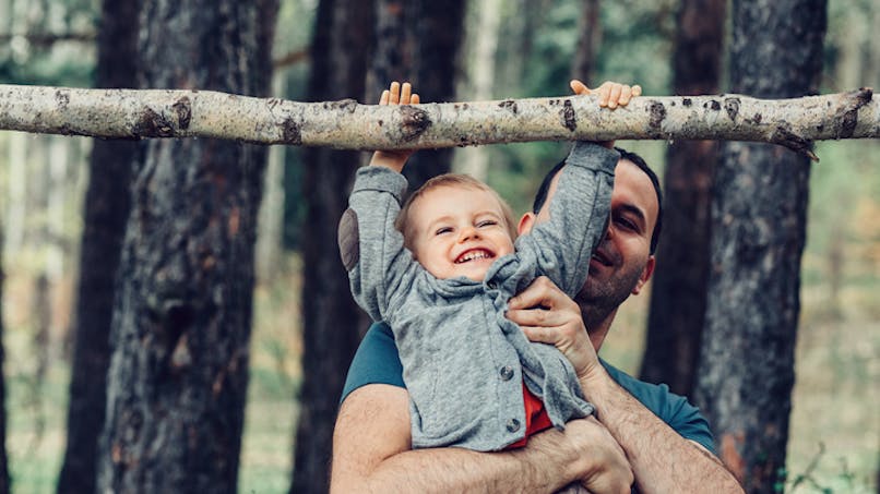 bébé joue dans arbre avec papa