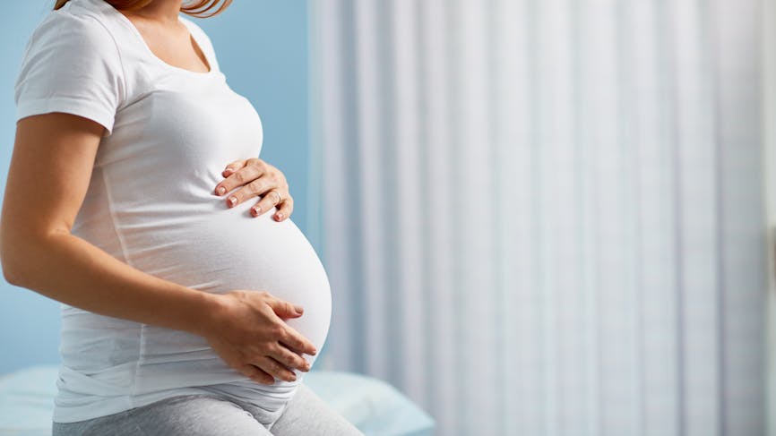 Une femme enceinte en fin de grossesse touche son ventre.
