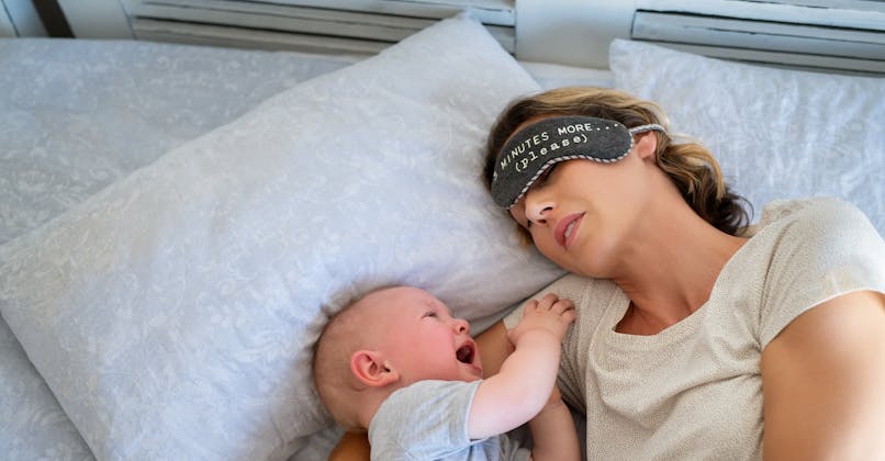 Une maman dort profondément alors que son bébé pleure.