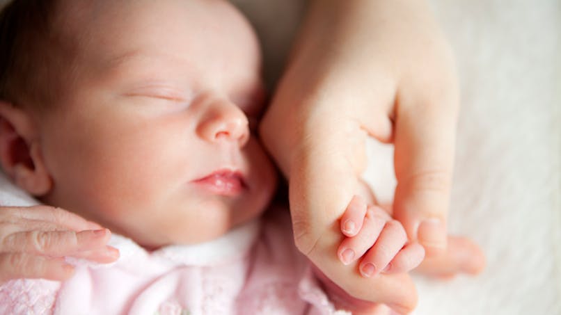 bébé endormi près de la main de maman