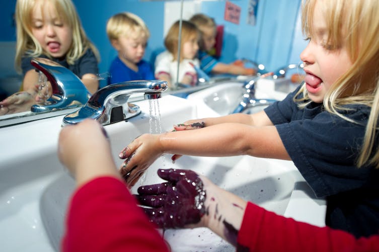 Des enfants se lavent les mains dans les toilettes d'une école.