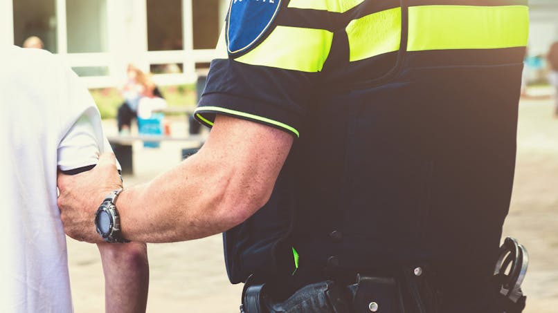 Un policier maintient un enfant par son bras.