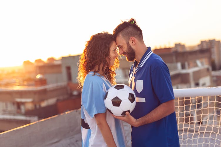 Un couple avec un ballon de football entre eux.