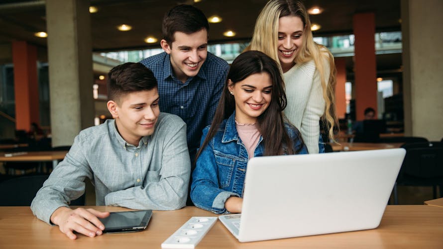 Étudiants qui regardent l'écran d'un ordinateur en souriant.