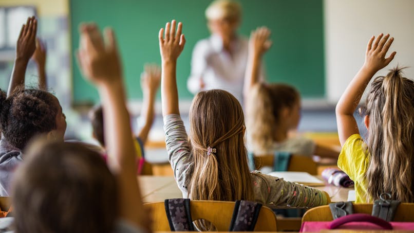 Des enfants lèvent la main pendant un cours.