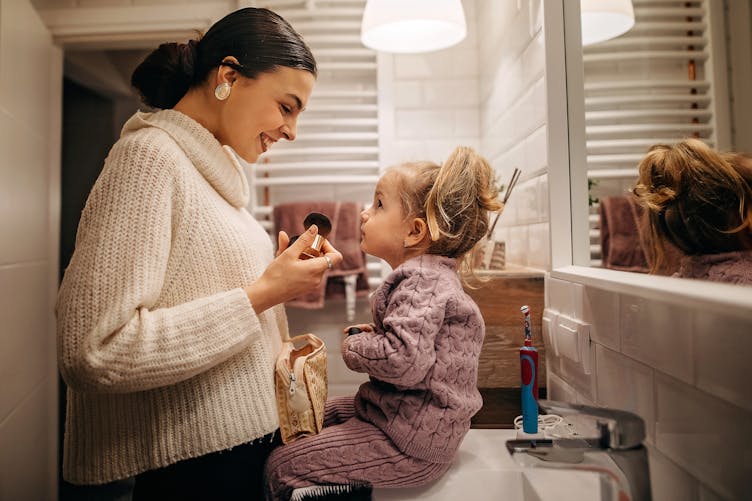 Une petite fille et sa maman dans une salle de bain.