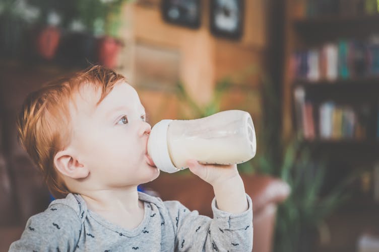 Petit garçon qui boit du lait dans un biberon.