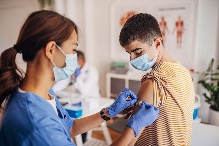 Une professionnelle de santé vaccine un jeune adolescent
