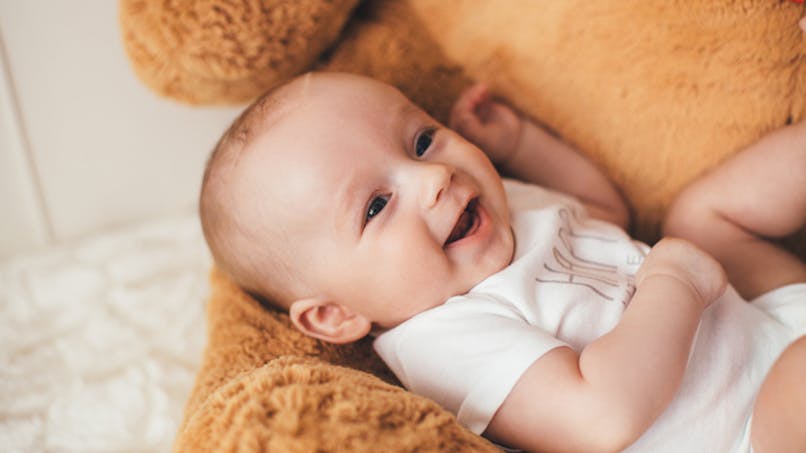 bébé souriant près d'une peluche