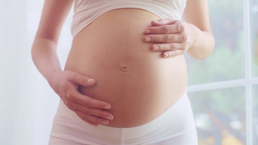 Une femme enceinte qui touche son ventre. 