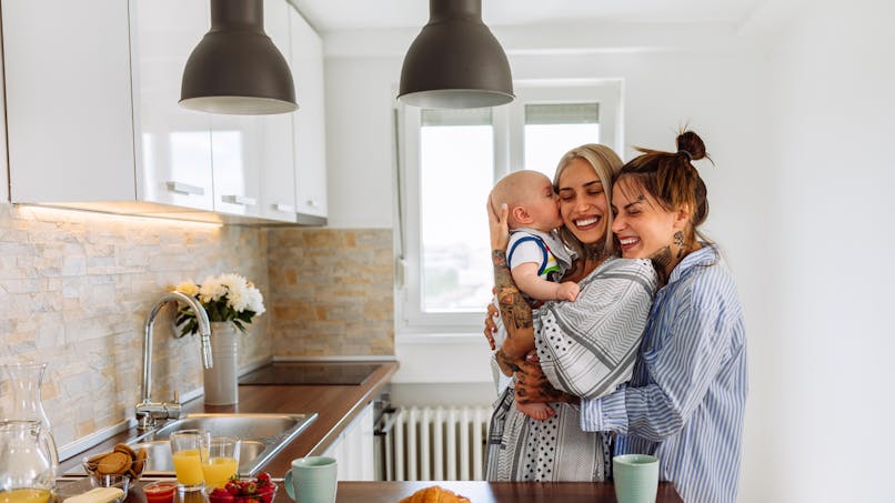 Un couple de femmes cajolent leur bébé dans leur cuisine
