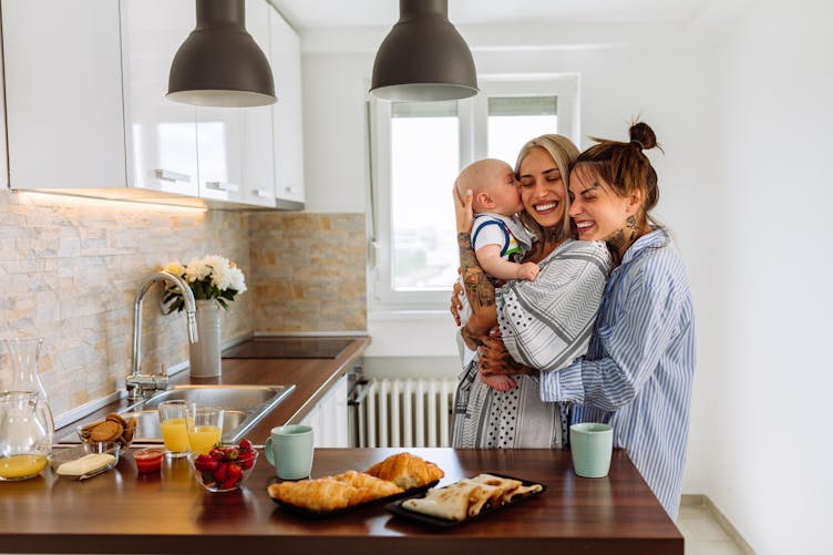 Un couple de femmes cajolent leur bébé dans leur cuisine