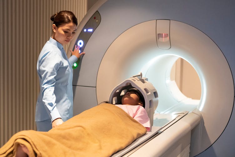 Une fillette s'apprête à passer une IRM et est accompagnée par une professionnelle de santé