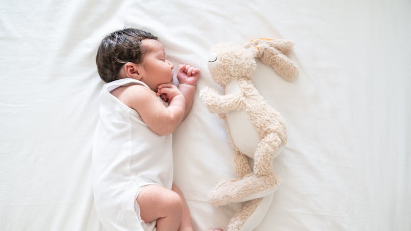 bébé couché avec doudou