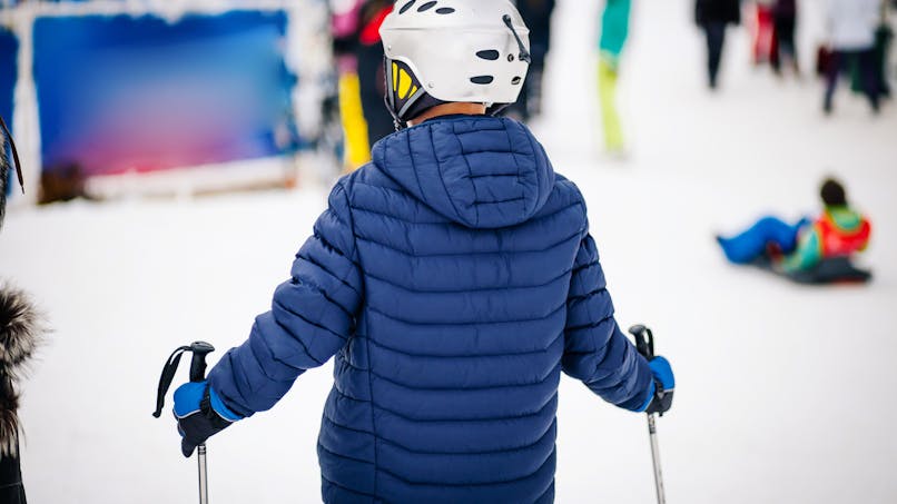 Un jeune garçon de dos fait du ski dans une station de ski