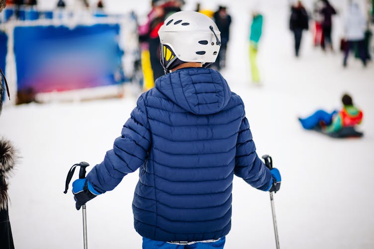 Un jeune garçon de dos fait du ski dans une station de ski
