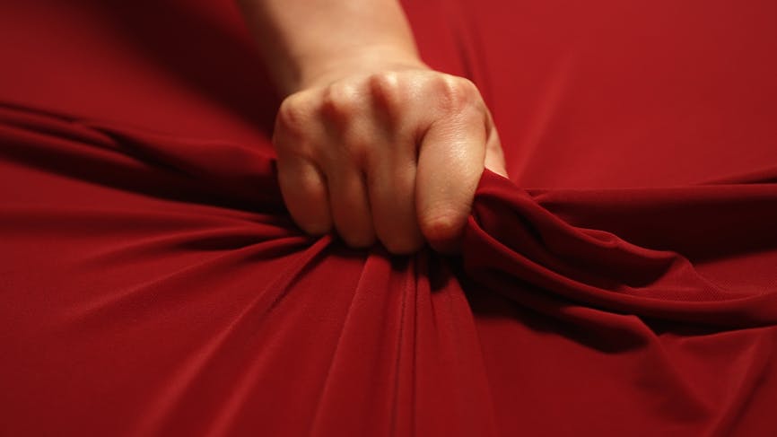 Main serrant un drap rouge