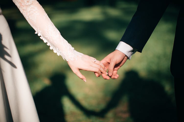 Un couple en tenue de mariés se tient la main