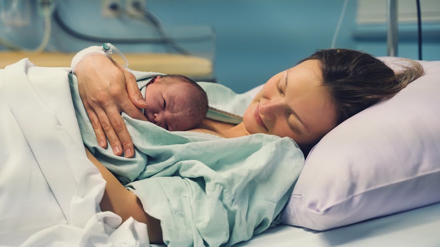 Une femme allongée à l'hôpital avec un nouveau né. 