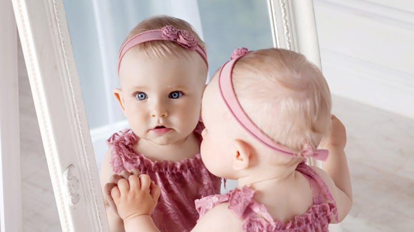bébé se regarde dans un miroir