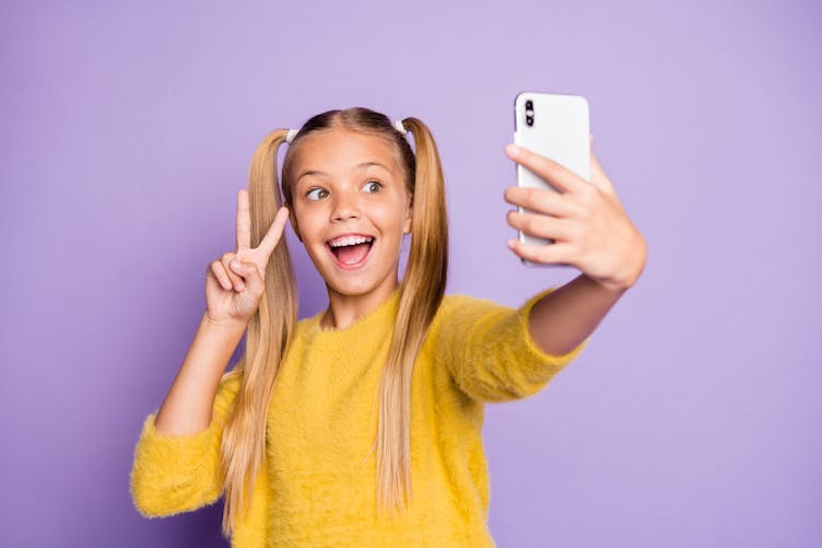 Une petite fille fait un selfie avec un smartphone.