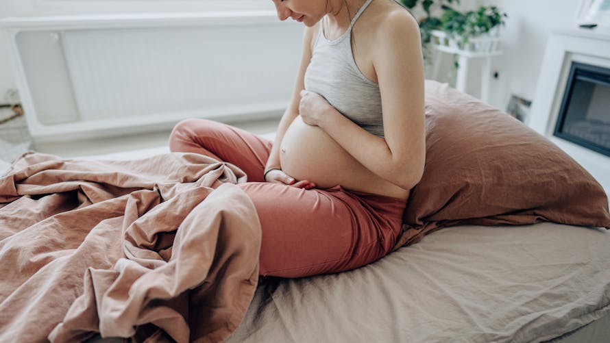 Femme enceinte tenant son ventre avec ses mains.