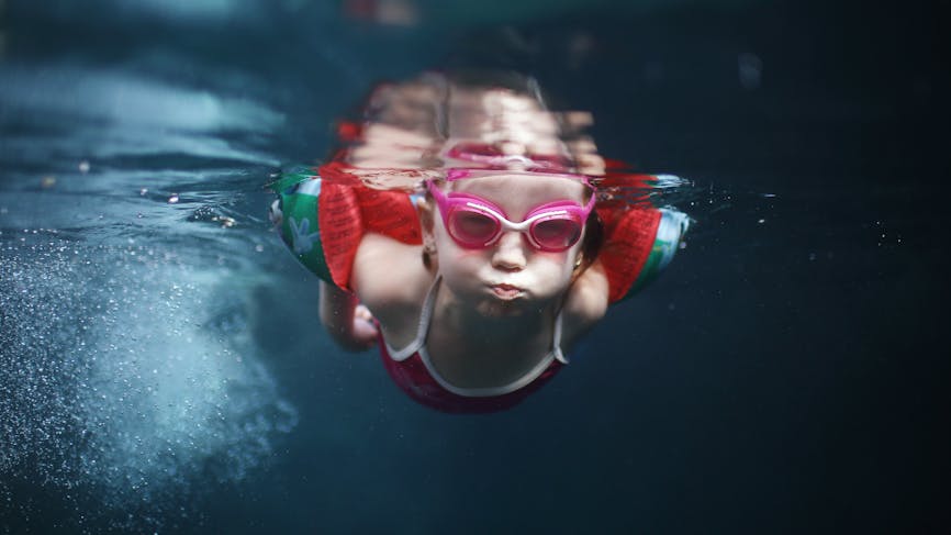Petite fille qui nage sous l'eau avec des brassards