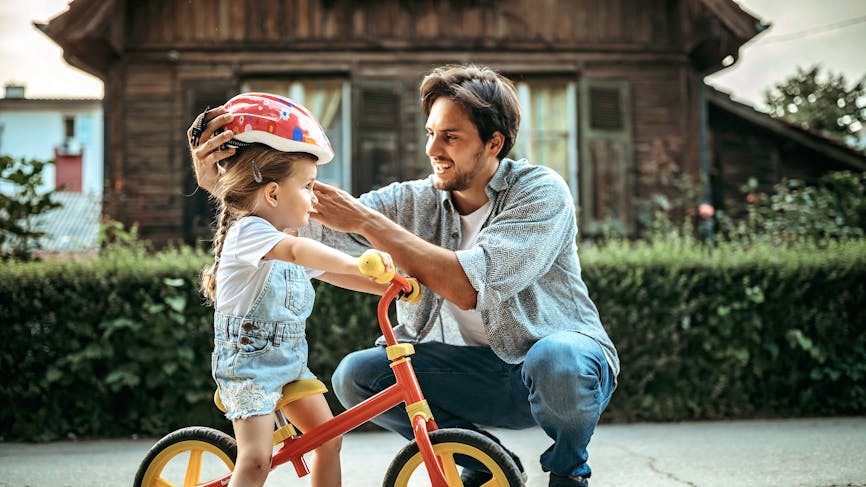 Un père préparant sa fille à faire du vélo
