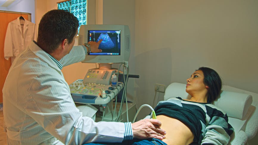 Un gynécologue montre l'écran à une jeune femme durant une échographie abdominale