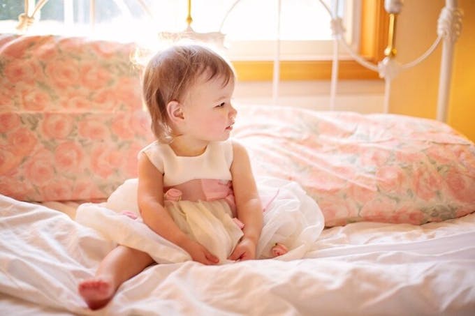 petite fille en robe sur un lit