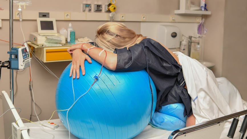 Femme s'aidant d'un ballon pour soulager les contractions.