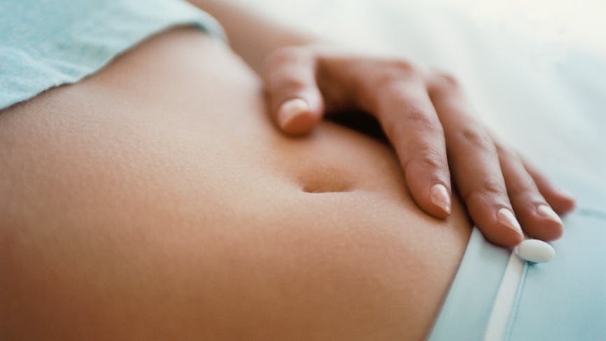 Une femme se touchant le ventre. 