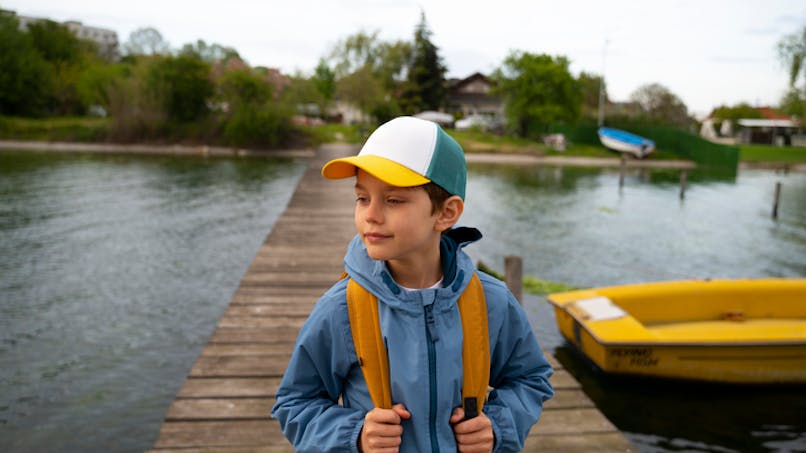 garçon portant une casquette devant un lac