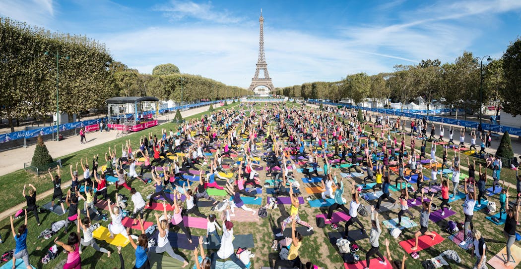 Nombreuses personnes faisant du yoga devant la Tour Eiffel