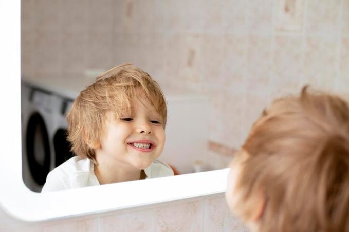 petit garçon se regardant miroir salle de bains